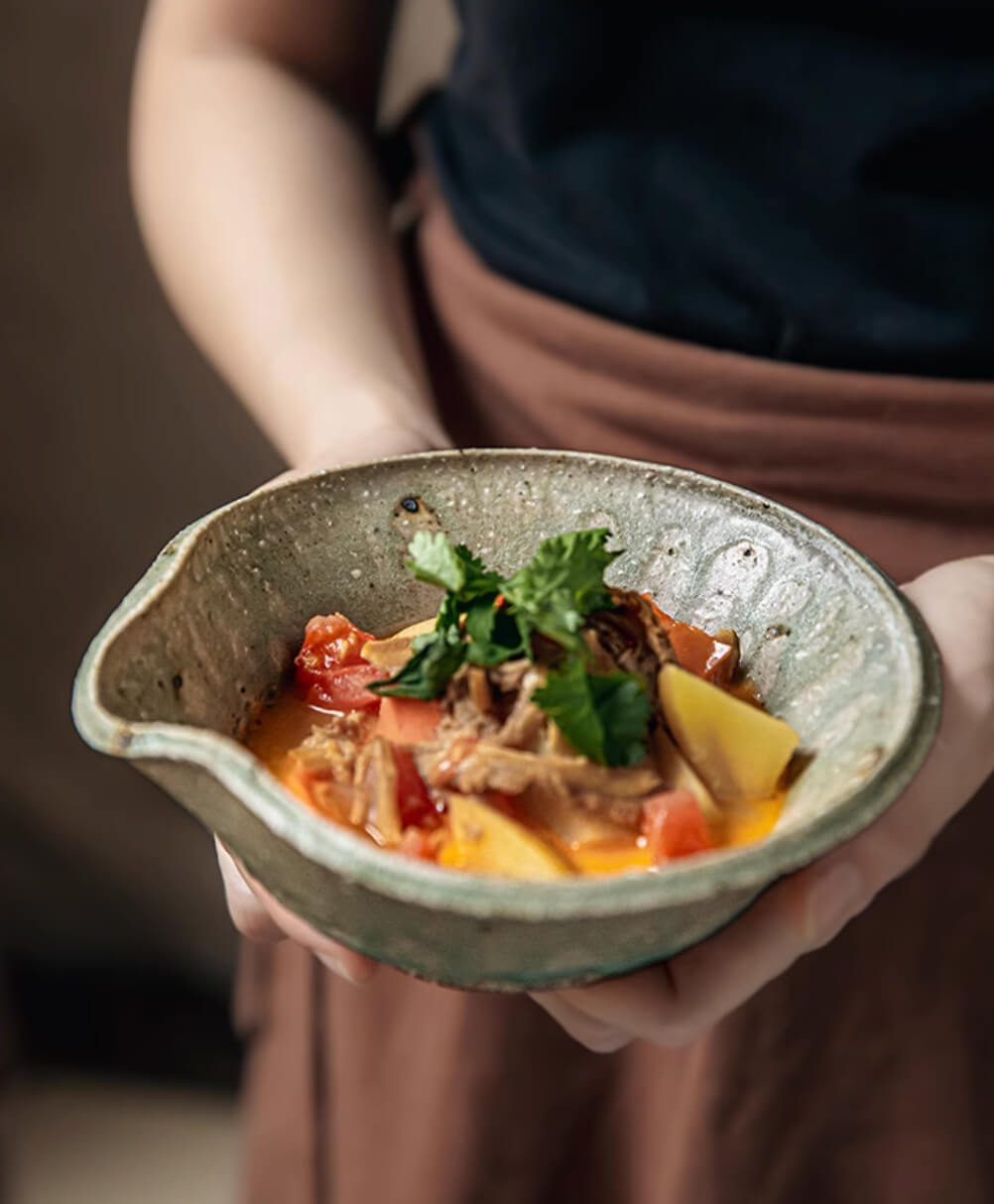 Artisan Green Dinnerware serving hearty stew with tomato & potatoes, garnished with fresh herbs.